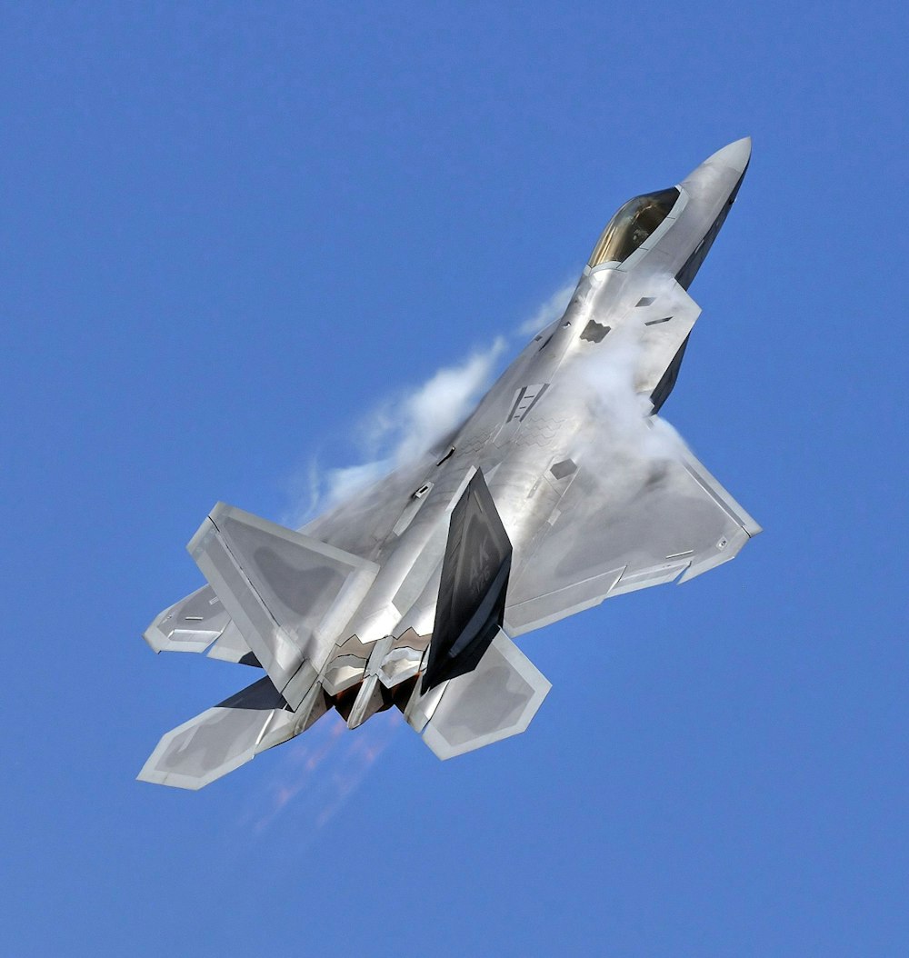 a silver fighter jet flying through a blue sky