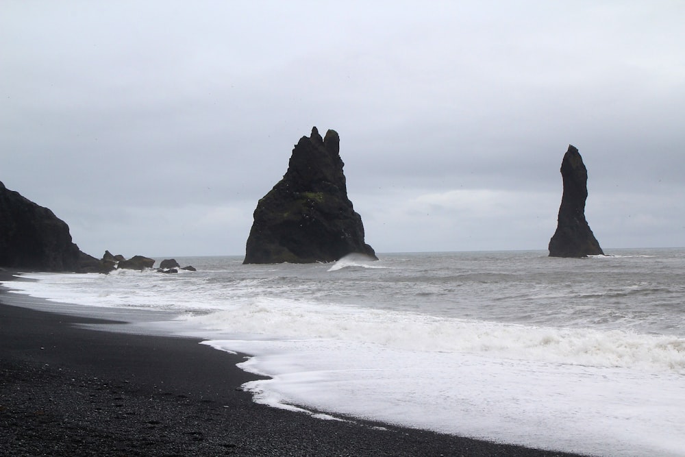 a black sand beach with a rock formation in the background