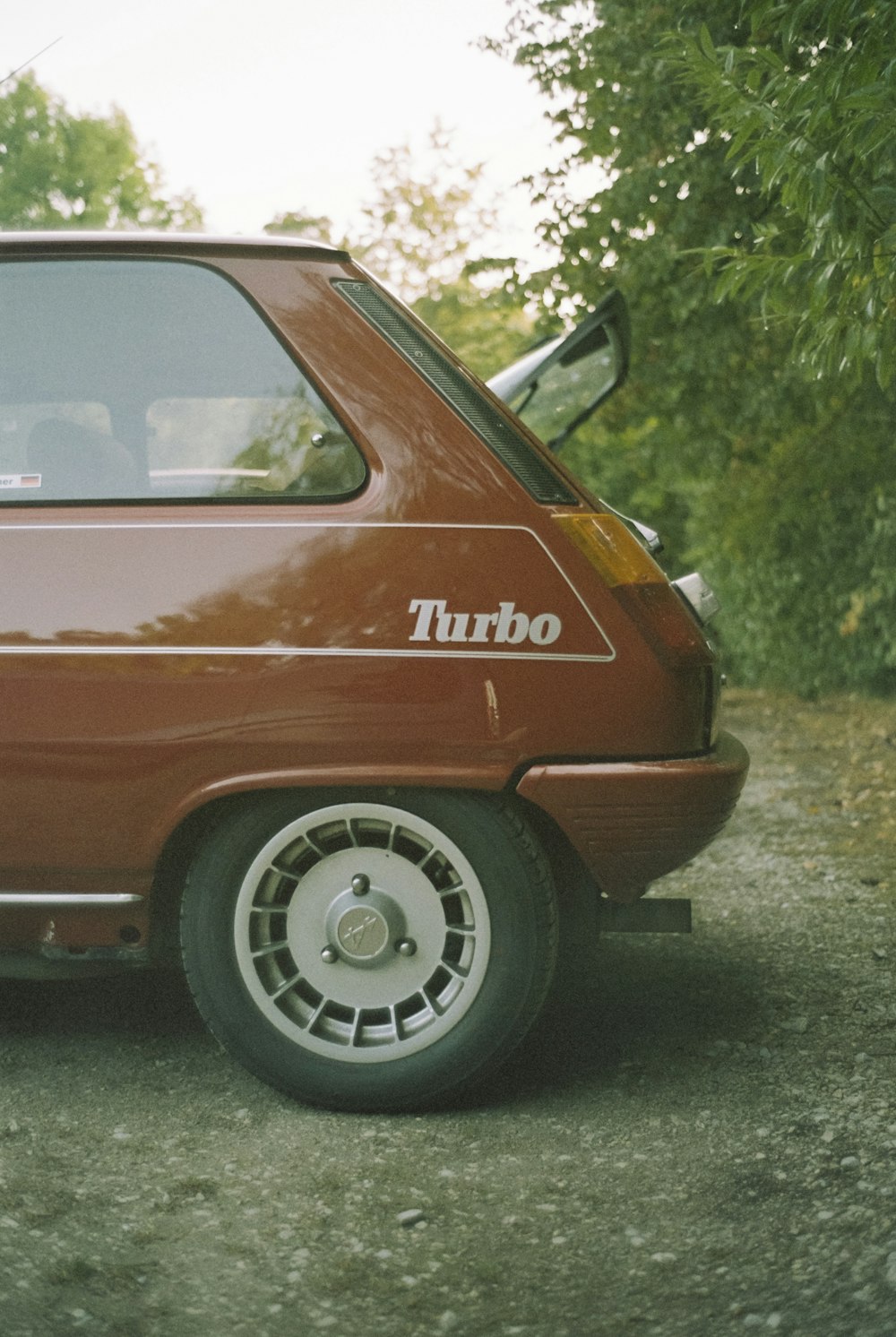 a small red car parked on a gravel road