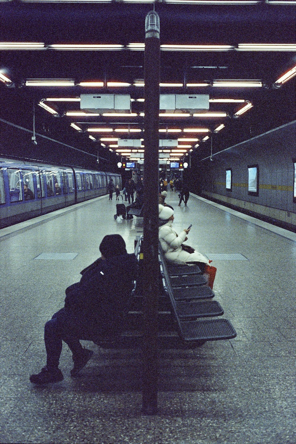 uma pessoa sentada em um banco em uma estação de trem
