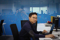 Person wearing smart glasses while working on a laptop in a bright, modern home office.