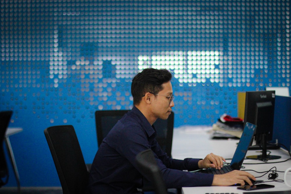 a man sitting at a desk using a laptop computer