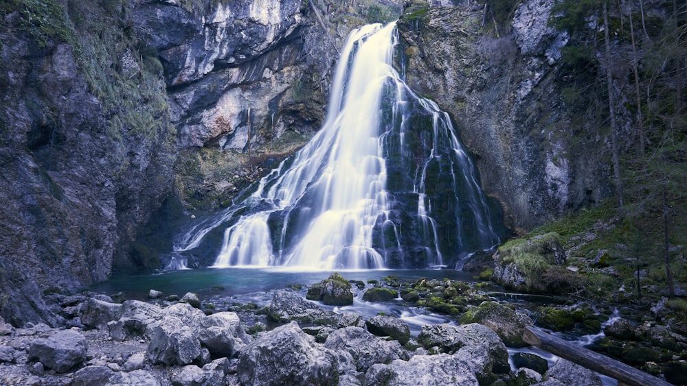 a large waterfall is in the middle of a rocky area