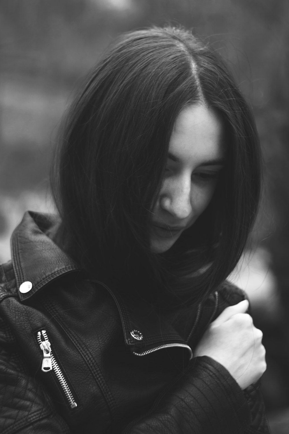 a woman in a leather jacket is looking down