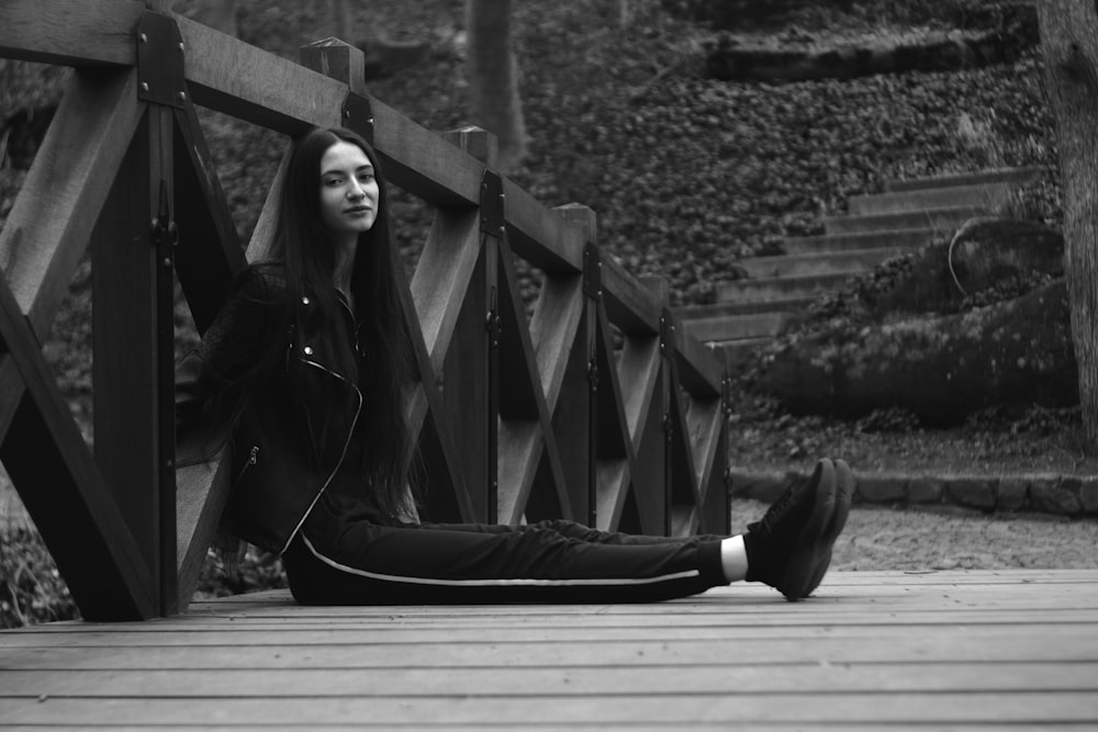 a woman is sitting on a wooden bridge