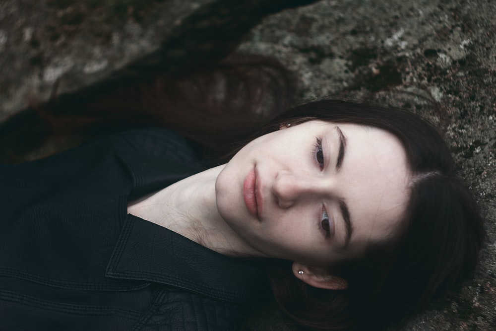 a woman laying on the ground next to a rock