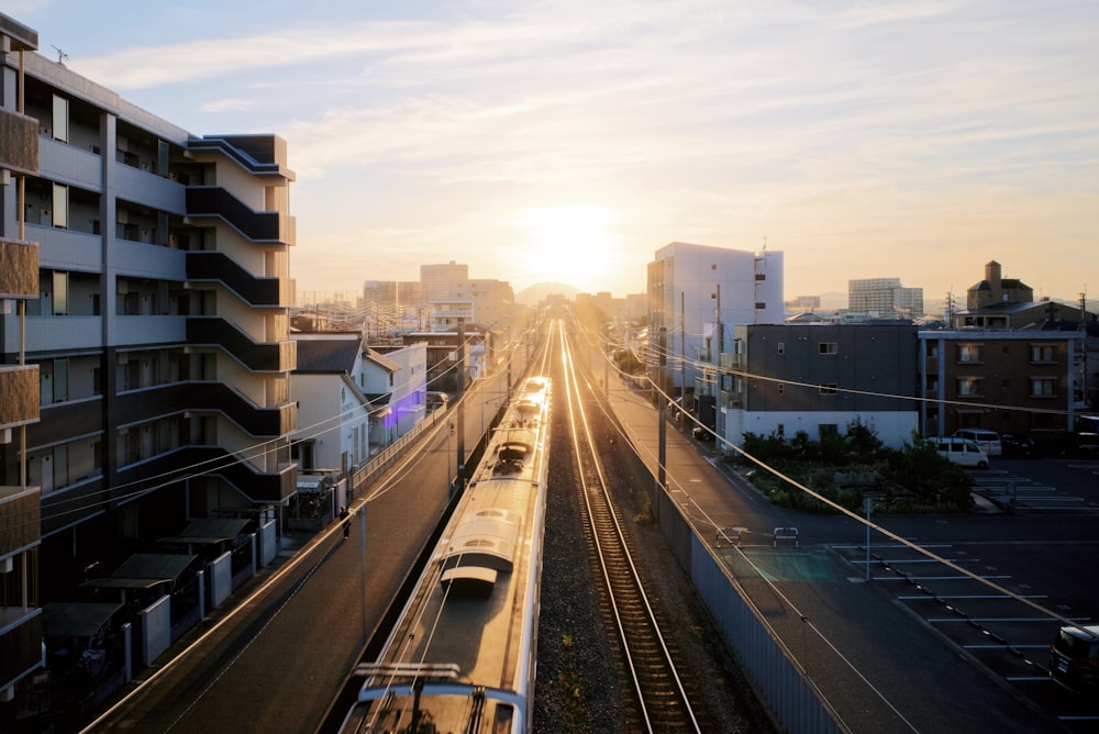 a train traveling down train tracks next to tall buildings