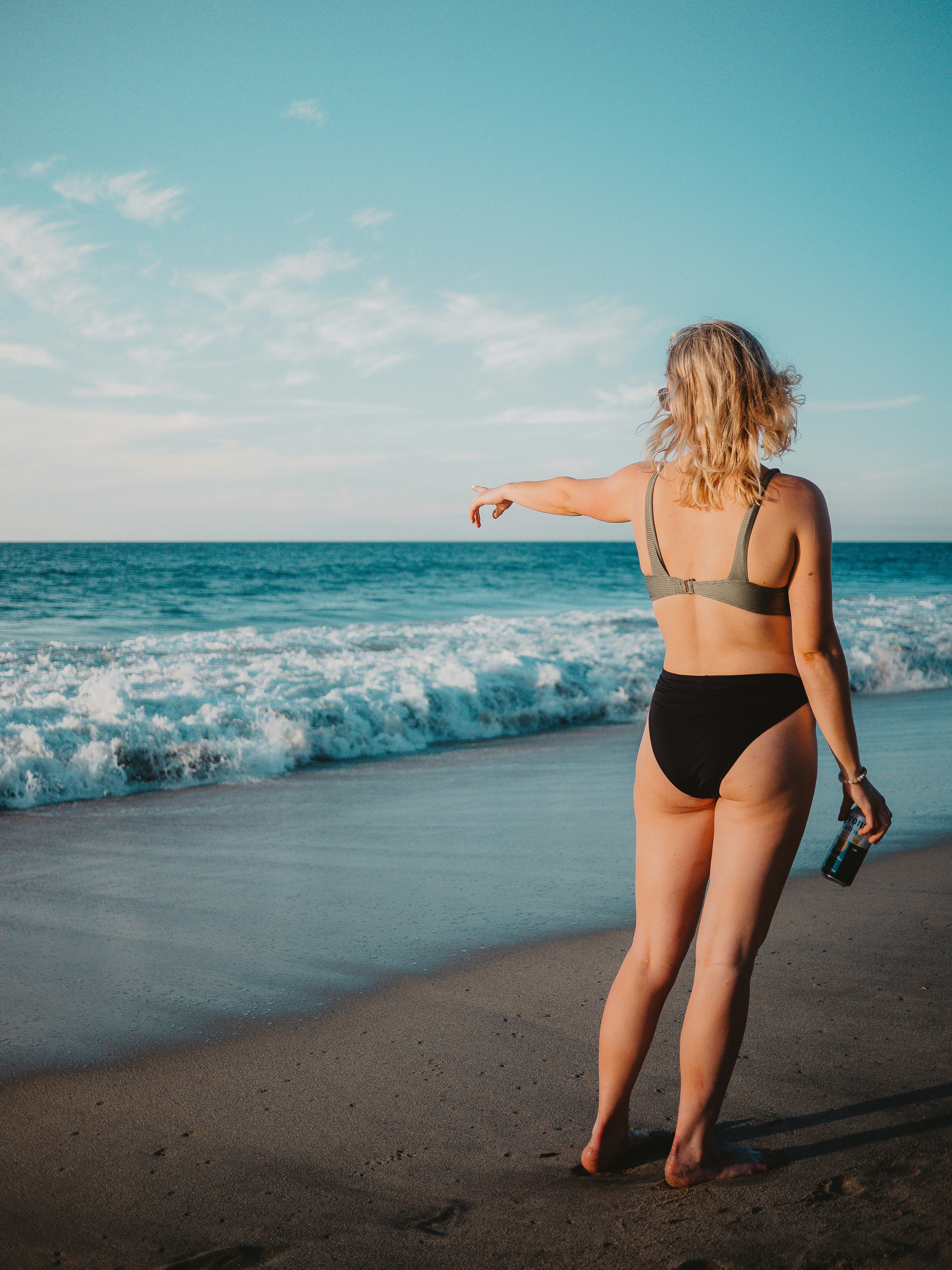a woman in a bikini pointing at the ocean