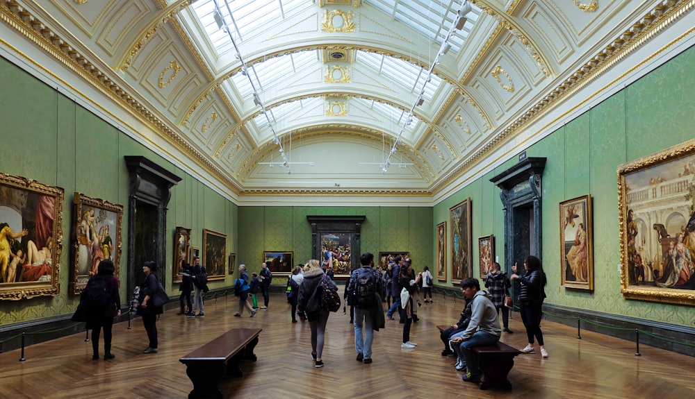 a group of people standing in a museum looking at paintings