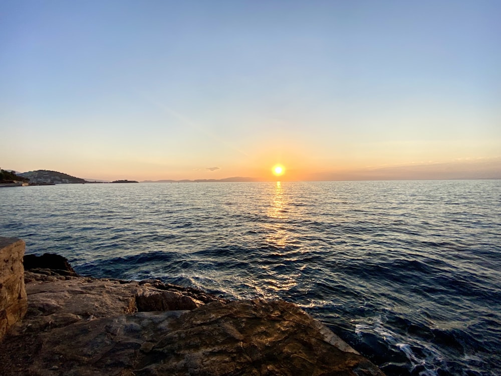 the sun is setting over the water at the beach