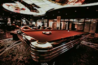 The cozy VIP lounge area featuring plush seating and golden accents beside a pool table.