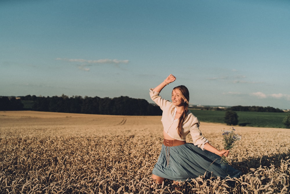 a woman standing in a field with her arms in the air