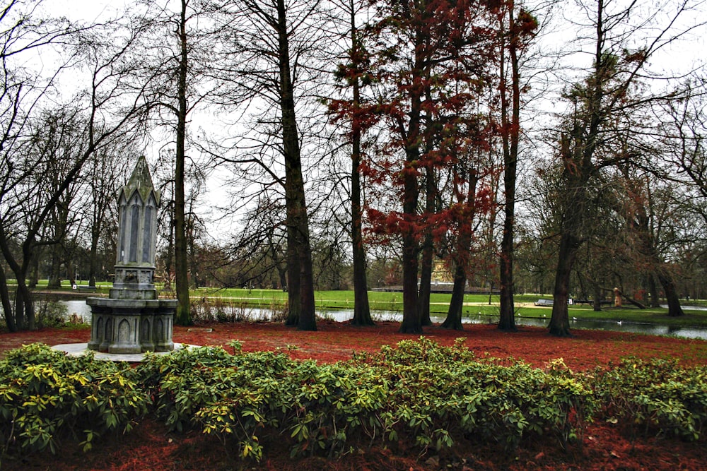 a statue in the middle of a park surrounded by trees