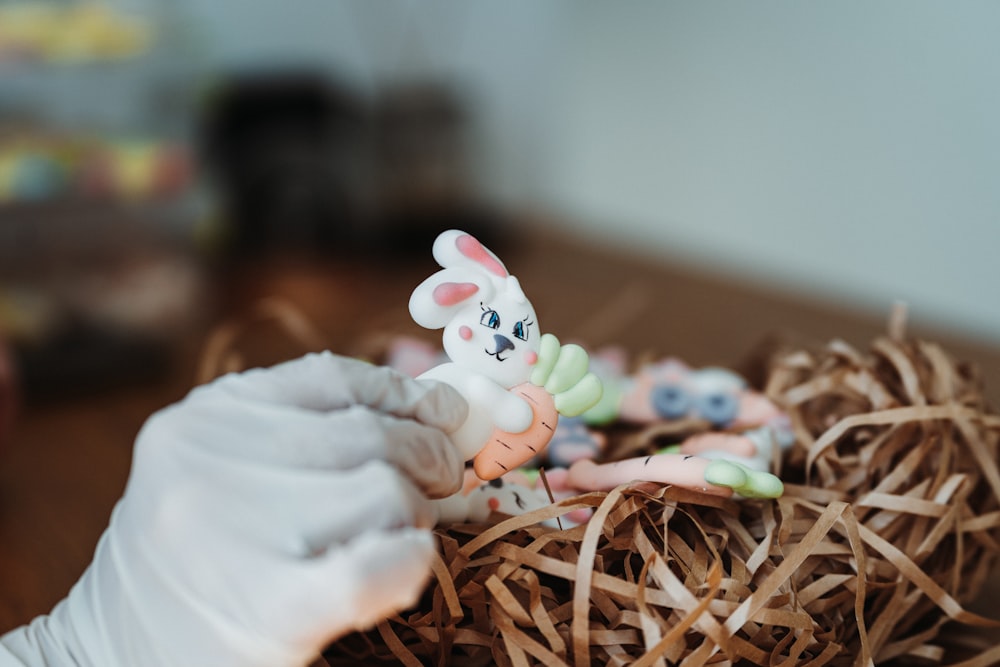 a close up of a person holding a toy rabbit in a nest