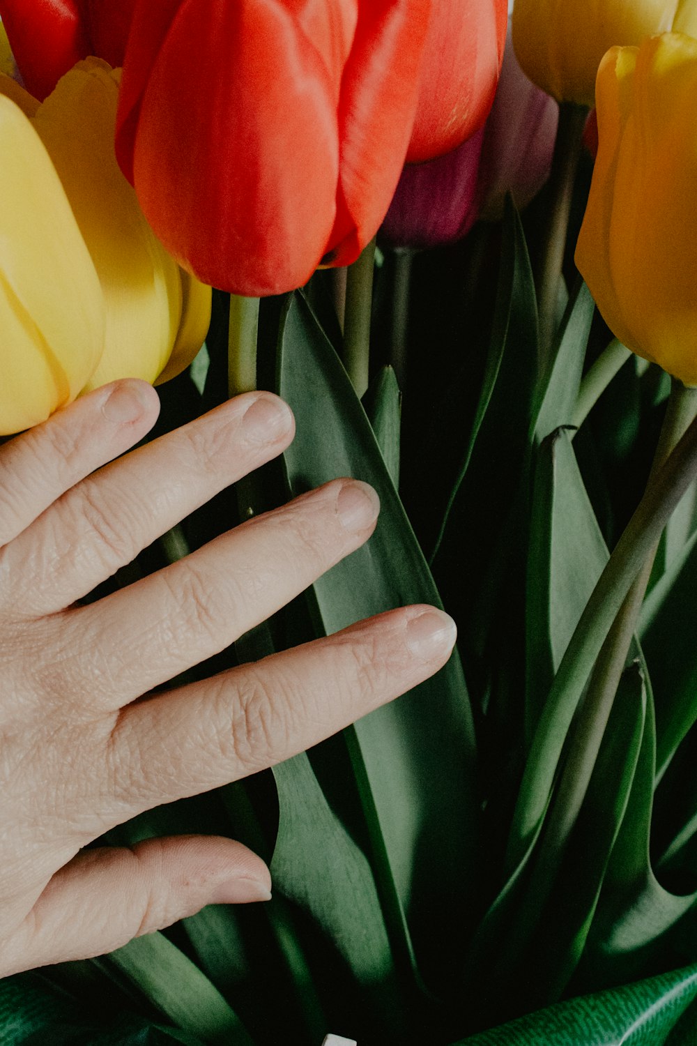 a close up of a person's hand near a bouquet of flowers