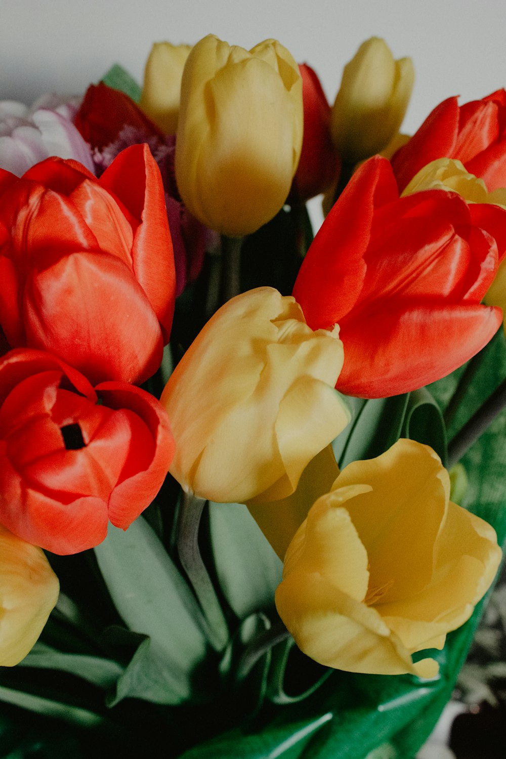 a vase filled with lots of red and yellow flowers