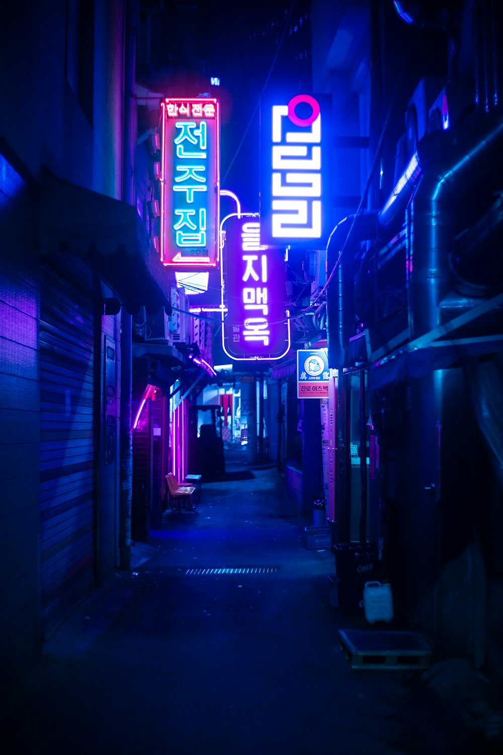 a narrow alley way with neon signs on it