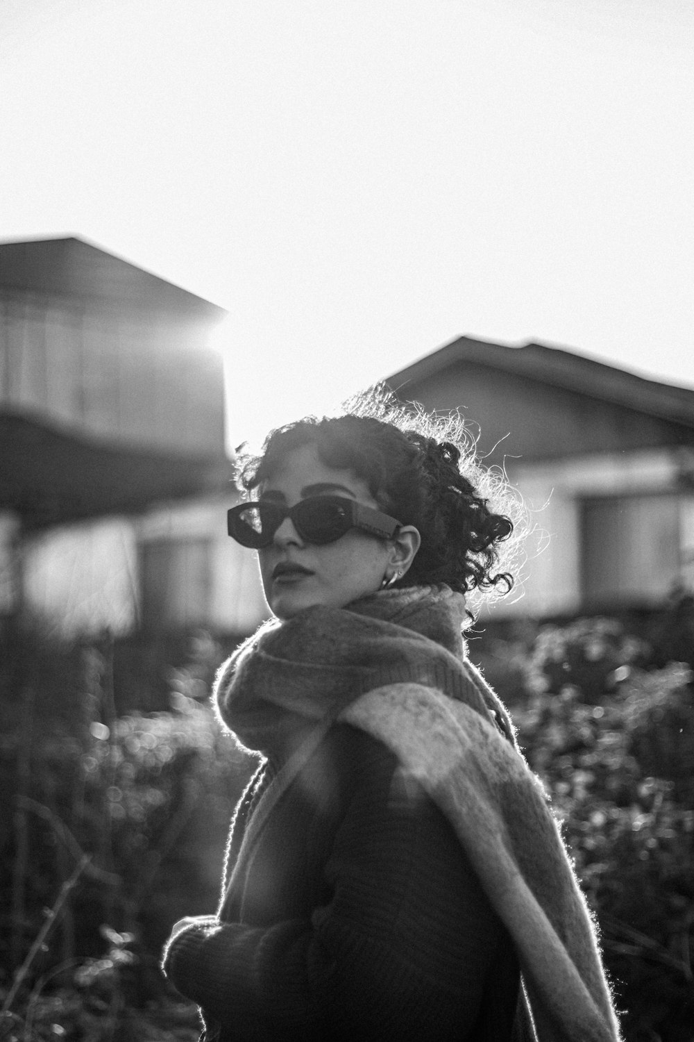 a woman wearing sunglasses standing in front of a house