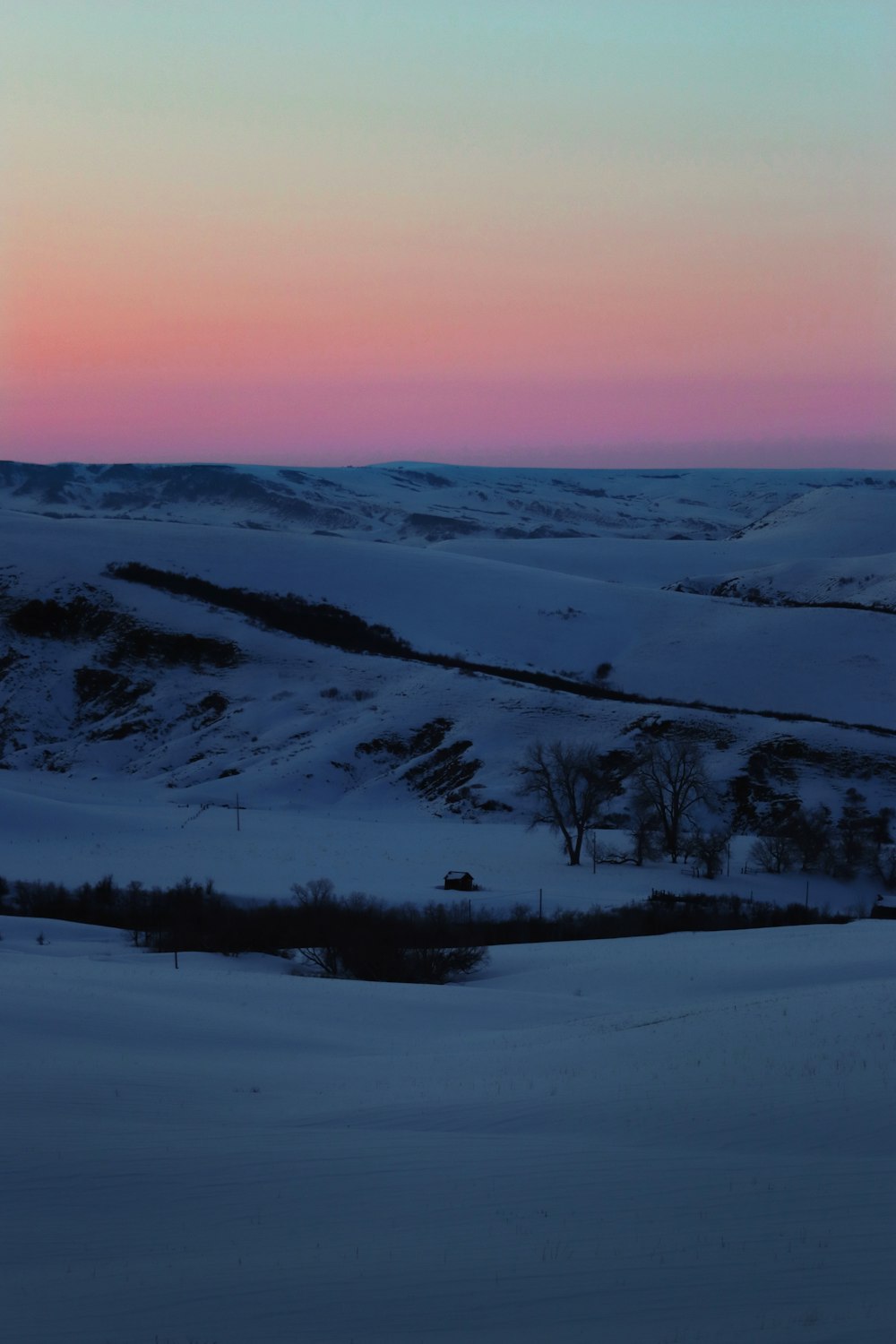 the sun is setting over a snowy landscape