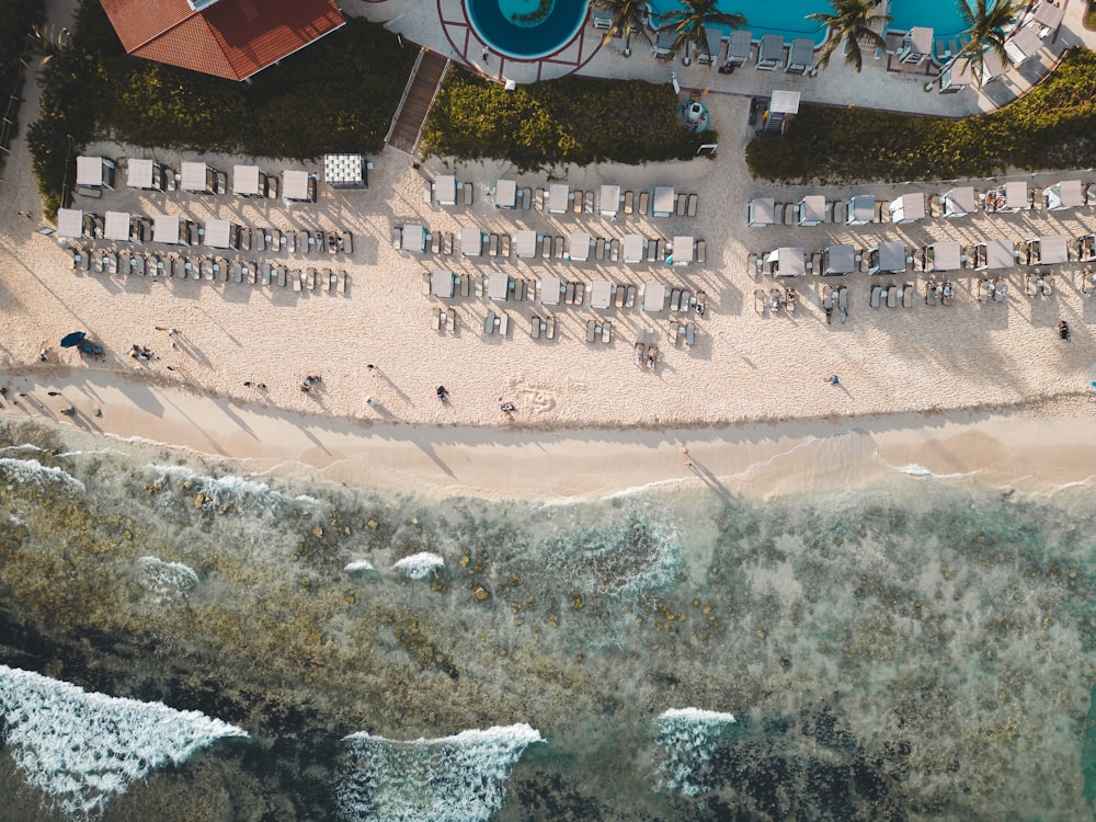 an aerial view of a beach with chairs and umbrellas