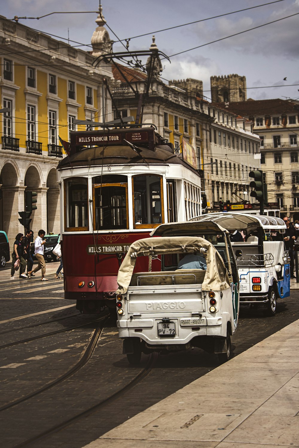 a red trolley car driving down a street next to a white car