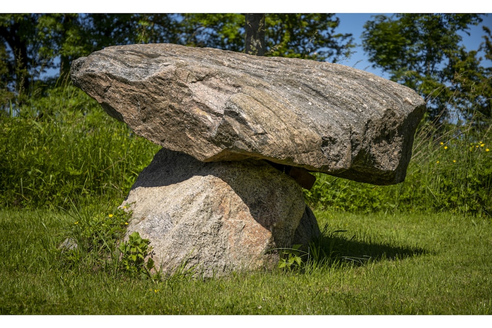 a large rock sitting on top of a lush green field