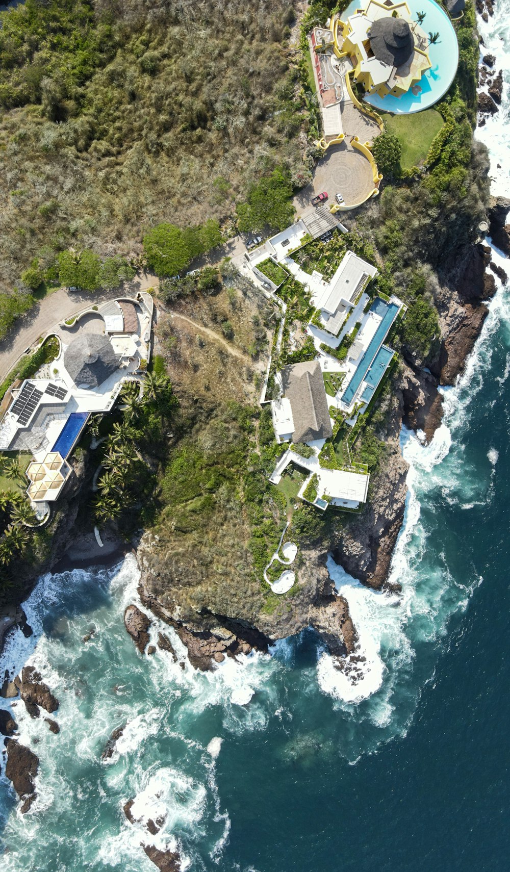 an aerial view of a house on a cliff next to the ocean