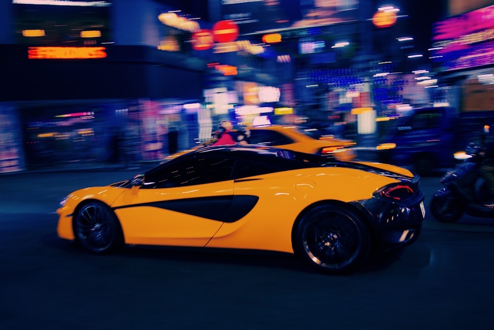 a yellow sports car driving down a city street