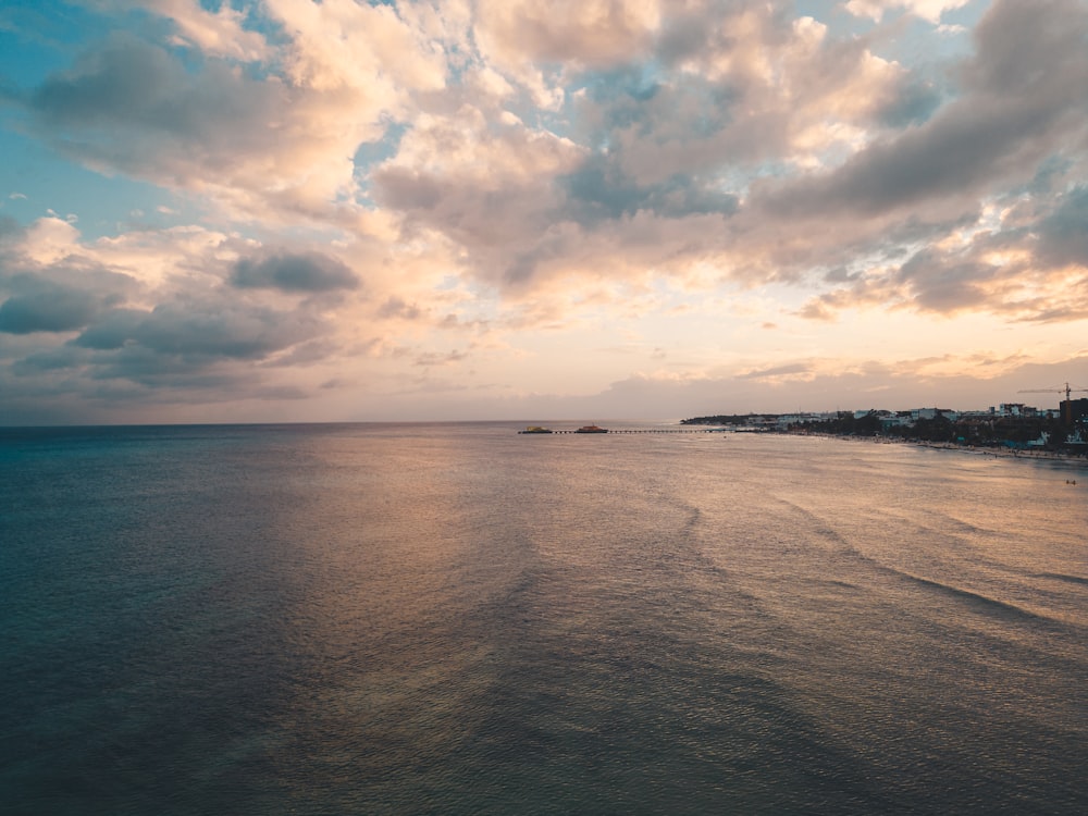 a body of water with a sky filled with clouds