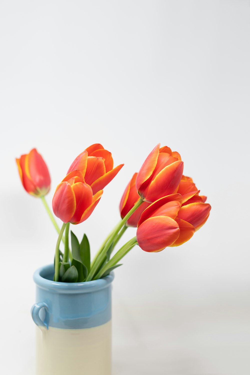 a blue and white vase filled with orange flowers