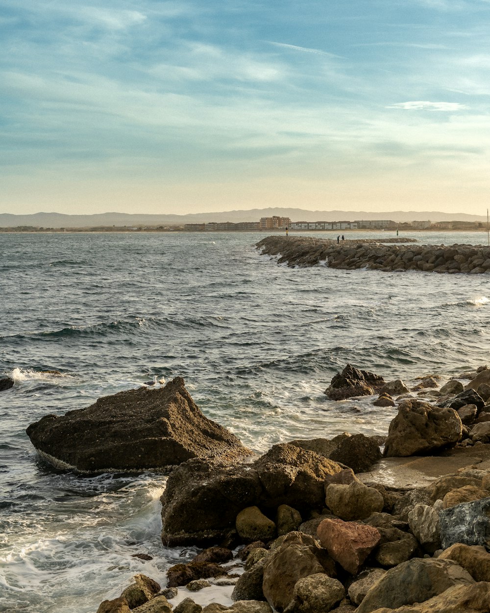 a rocky shore with a lighthouse in the distance