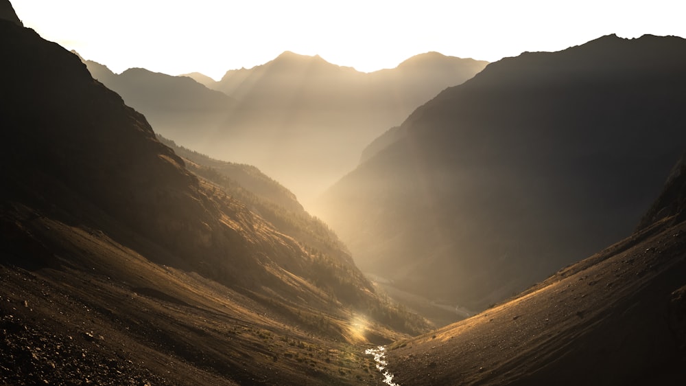 the sun shines through the mountains in the valley