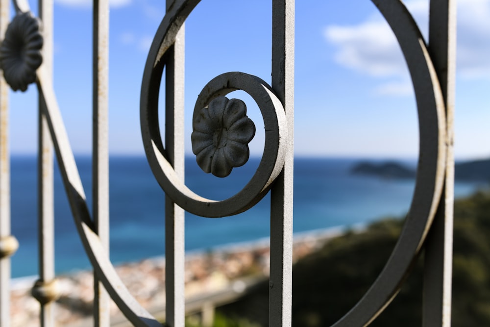 a close up of a metal fence with a view of the ocean