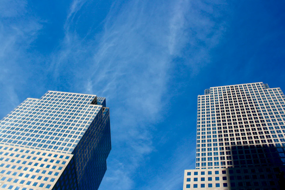 Two skyscrapers stand on either side of a street, reaching towards the clear blue sky