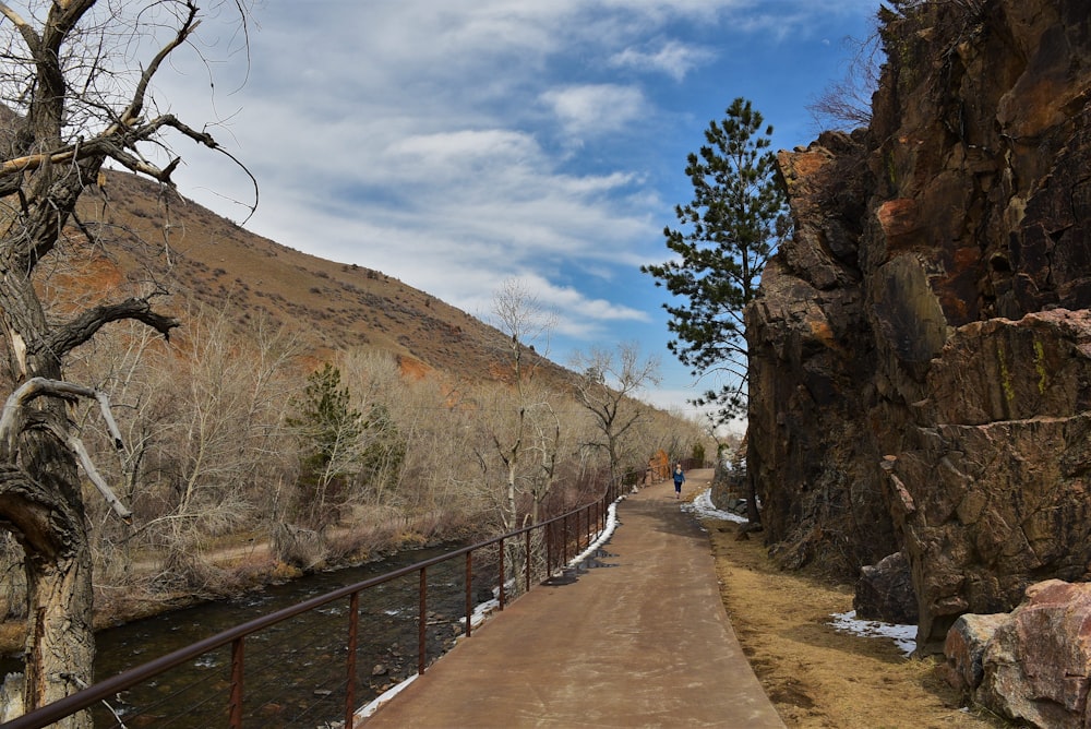 a dirt road next to a rocky cliff