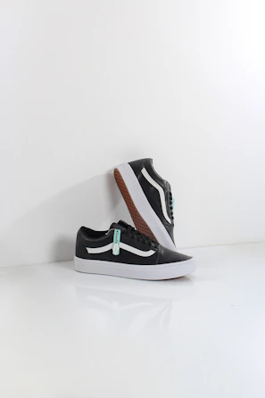 Close-up of sleek black leather sneakers with white soles on a minimalist white background.