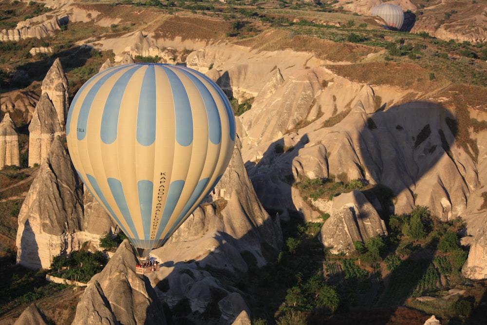 a hot air balloon flying over a rocky landscape
