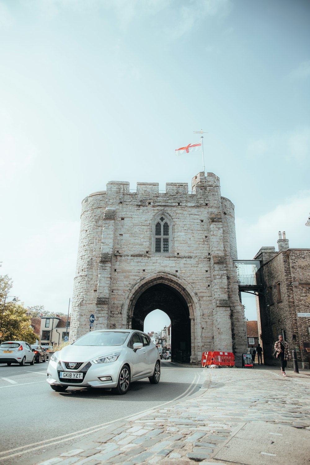 a white car parked in front of a stone gate