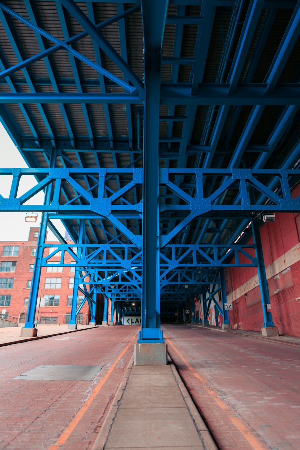 Una estructura de metal azul con un edificio de ladrillo rojo en el fondo