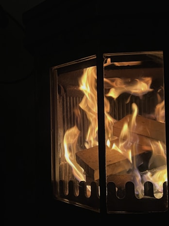 Close-up of a wood stove’s intricate ironwork with a backdrop of natural wood cabinets.