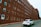 a white car driving down a street next to a tall brick building