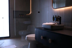 a bathroom with a toilet, sink and mirror