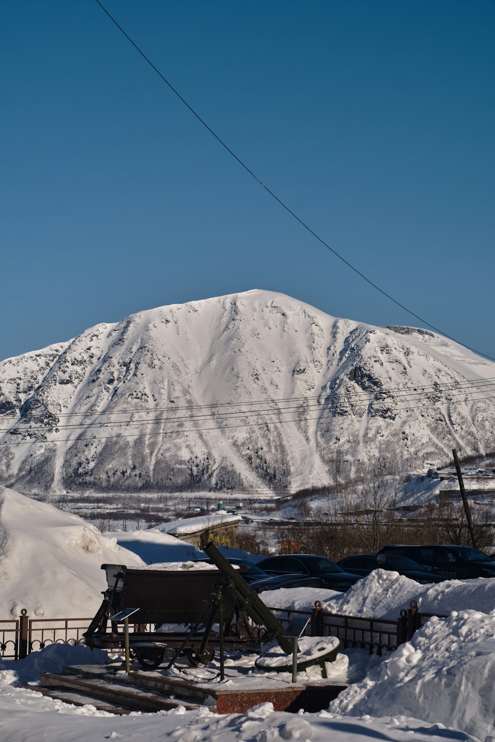 Una montagna coperta di neve con una linea elettrica in primo piano