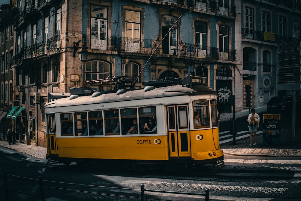 a yellow trolley car traveling down a street next to a tall building