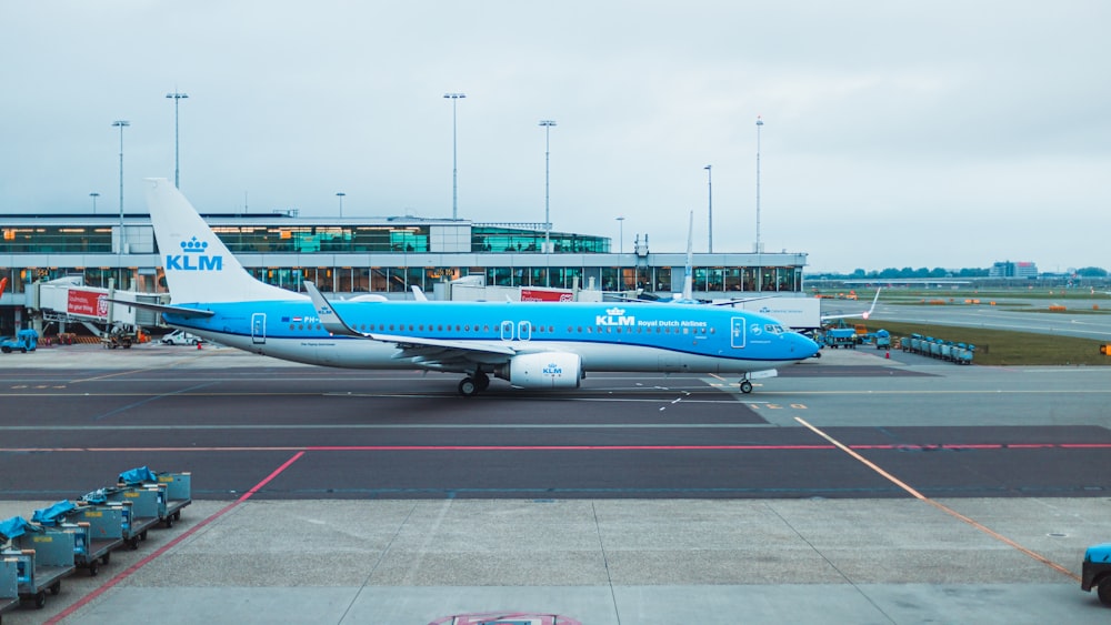 a blue and white jet airliner sitting on top of an airport tarmac