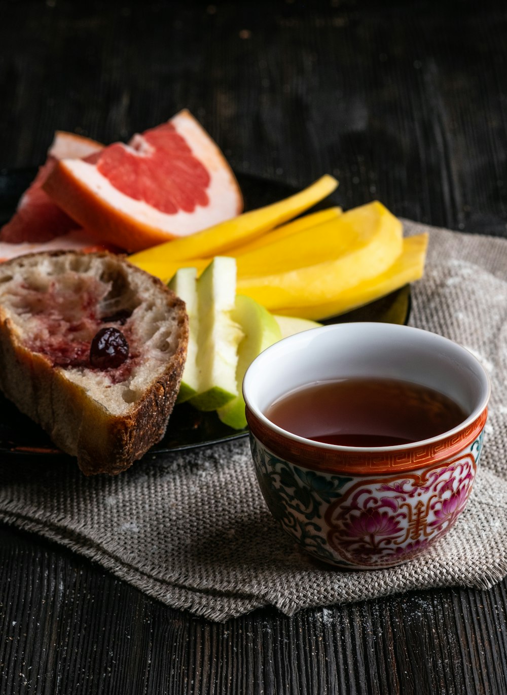 a cup of tea next to a plate of fruit