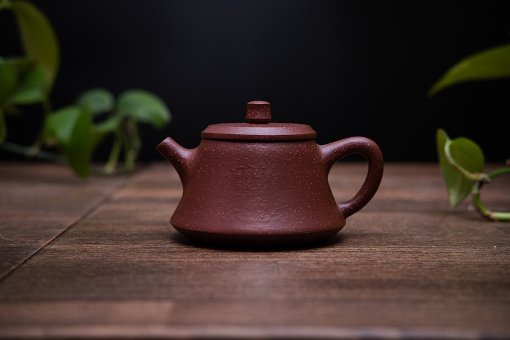 a brown tea pot sitting on top of a wooden table
