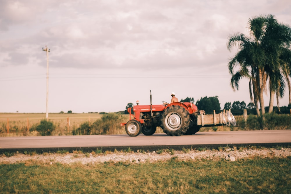 a red tractor driving down a rural road