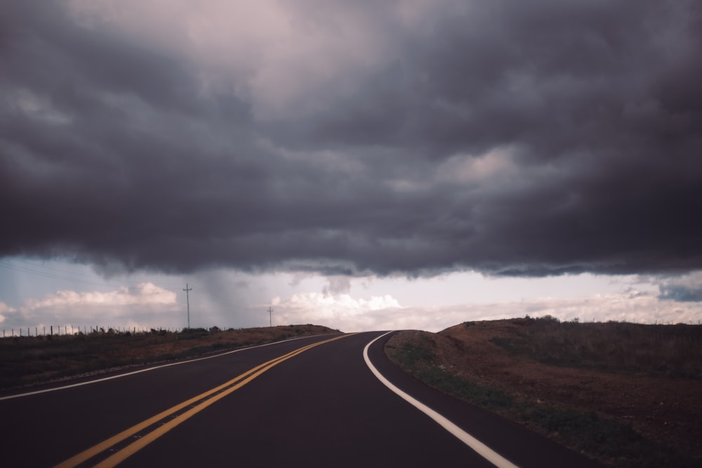 uma longa estrada com um céu cheio de nuvens escuras