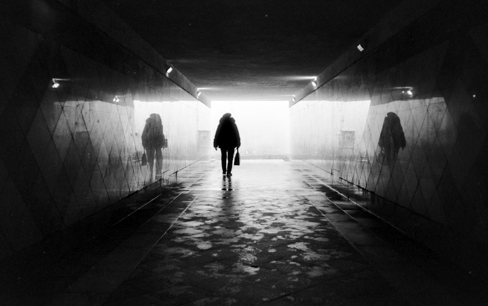 a person standing in a tunnel with a light at the end